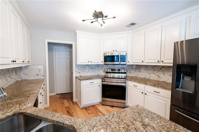 1200 Martins Chapel Ln SE, Lawrenceville, GA 30045 - kitchen featuring appliances with stainless steel finishes, light wood-type flooring, white cabinetry, and backsplash