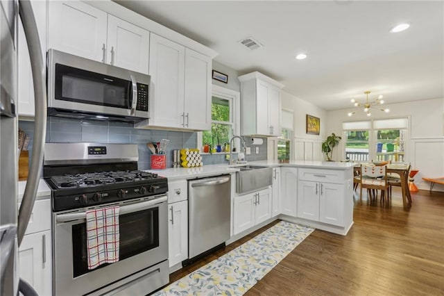 kitchen featuring a peninsula, light countertops, visible vents, appliances with stainless steel finishes, and a sink