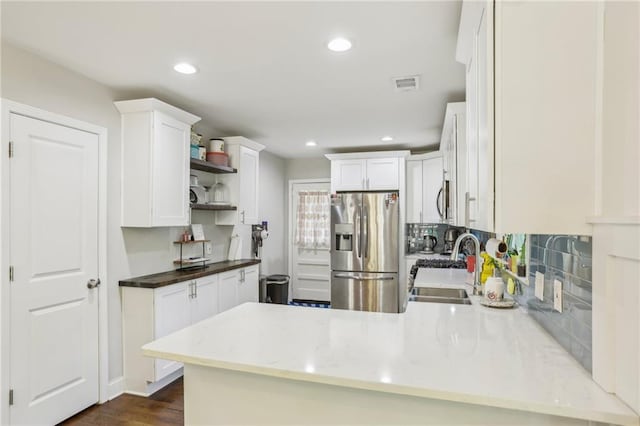 kitchen with visible vents, open shelves, a sink, appliances with stainless steel finishes, and a peninsula