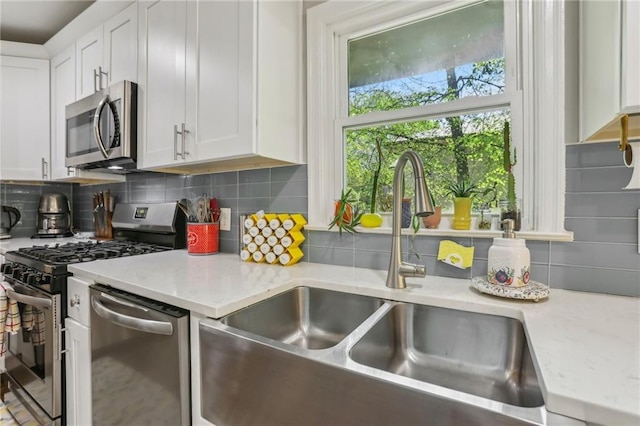 kitchen featuring a sink, backsplash, white cabinets, and stainless steel appliances