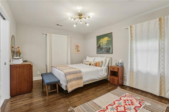 bedroom with a chandelier, wood finished floors, baseboards, and visible vents