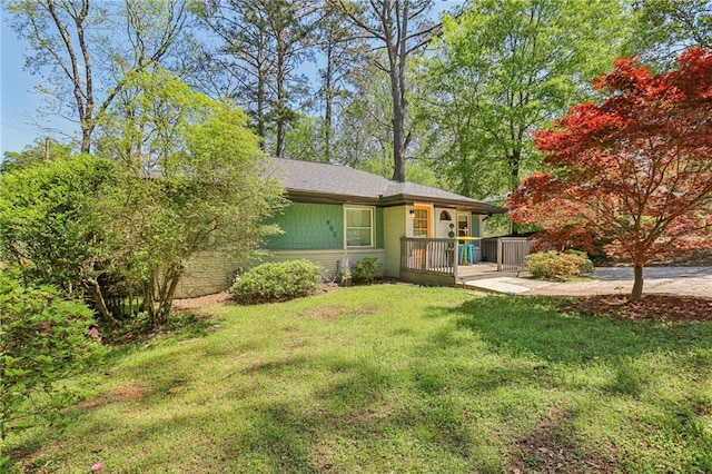 view of front of house featuring a front yard, a deck, and brick siding