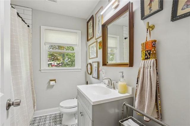 bathroom featuring tile patterned flooring, vanity, baseboards, and toilet