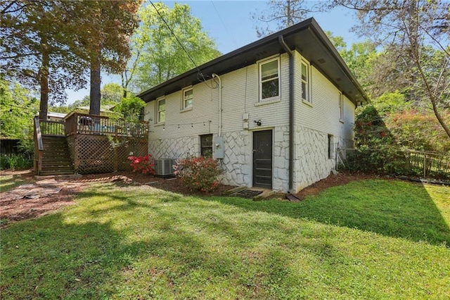 rear view of house with a lawn, a wooden deck, and stairs