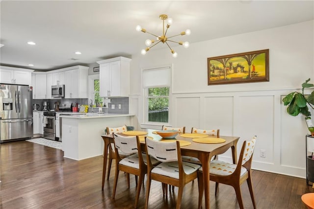 dining room with a notable chandelier, a decorative wall, recessed lighting, dark wood-type flooring, and a wainscoted wall