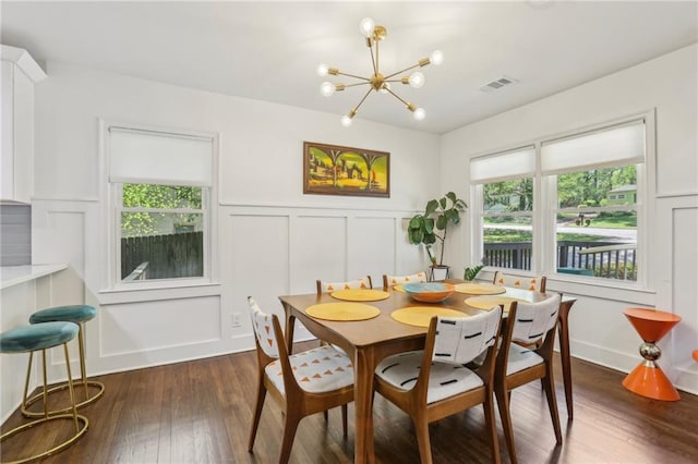 dining area with a decorative wall, visible vents, a chandelier, and dark wood-type flooring