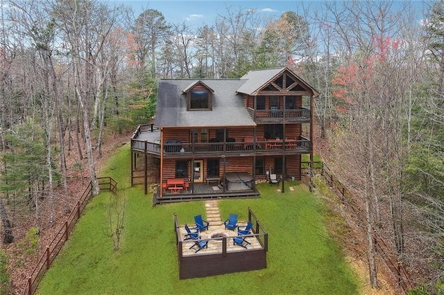 back of property with a deck, a lawn, and an outdoor living space with a fire pit