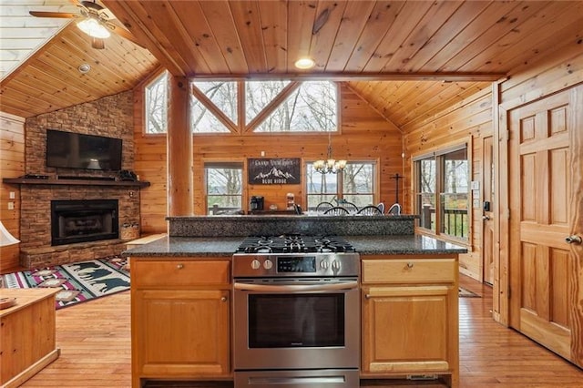 kitchen with gas range, a kitchen island, a fireplace, and wooden walls