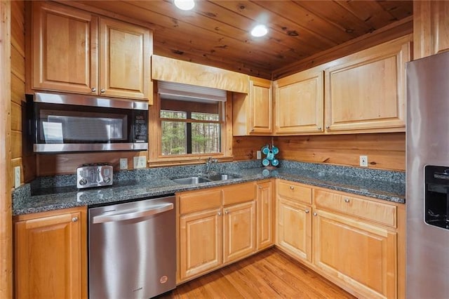 kitchen with appliances with stainless steel finishes, sink, dark stone countertops, wooden ceiling, and light wood-type flooring