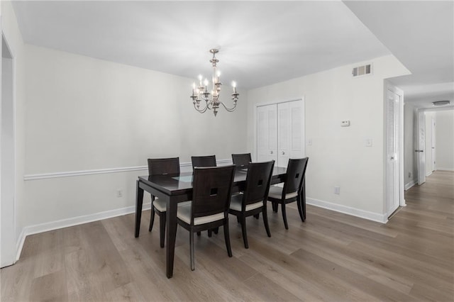 dining room featuring visible vents, a notable chandelier, baseboards, and wood finished floors