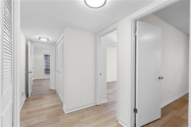 hallway featuring light wood-style flooring and baseboards