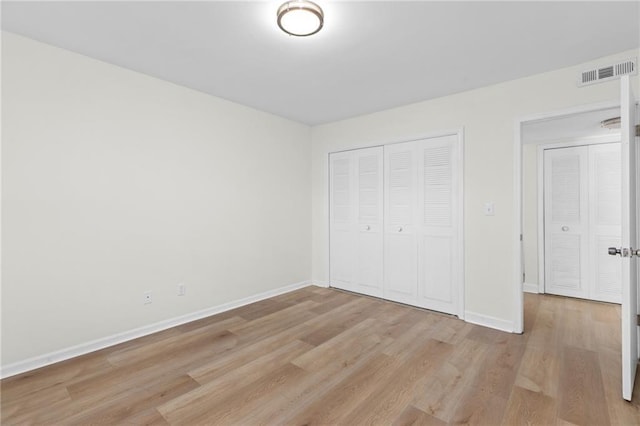 unfurnished bedroom with a closet, baseboards, visible vents, and light wood finished floors