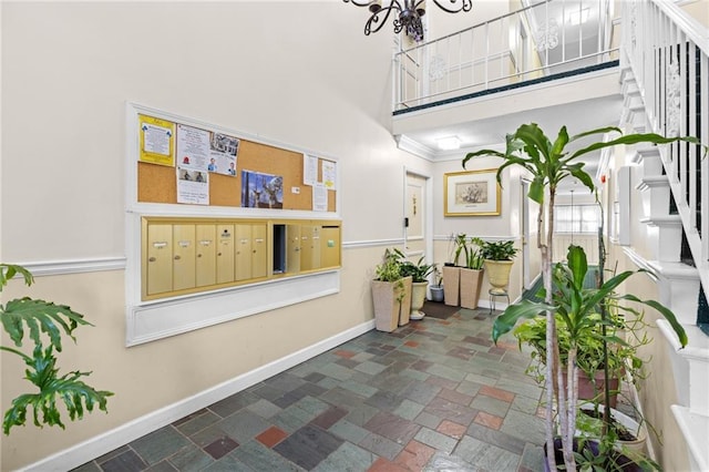 corridor featuring a towering ceiling, mail area, and baseboards