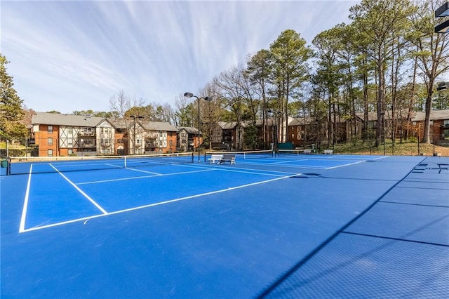 view of tennis court with a residential view and fence