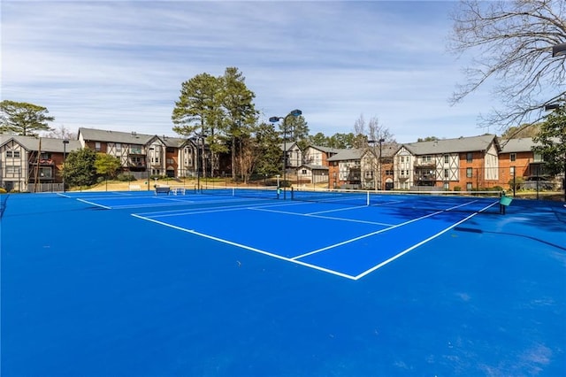 view of tennis court with fence and a residential view