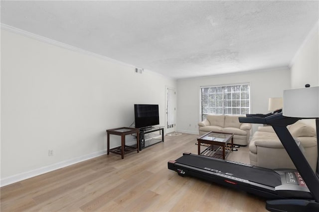 workout area with visible vents, ornamental molding, a textured ceiling, light wood-type flooring, and baseboards