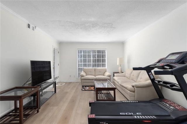 living room featuring a textured ceiling, ornamental molding, light wood-type flooring, and visible vents