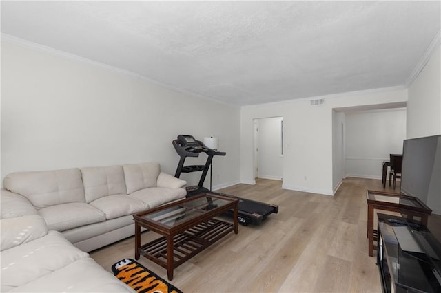 living room featuring light wood finished floors, baseboards, visible vents, ornamental molding, and a textured ceiling