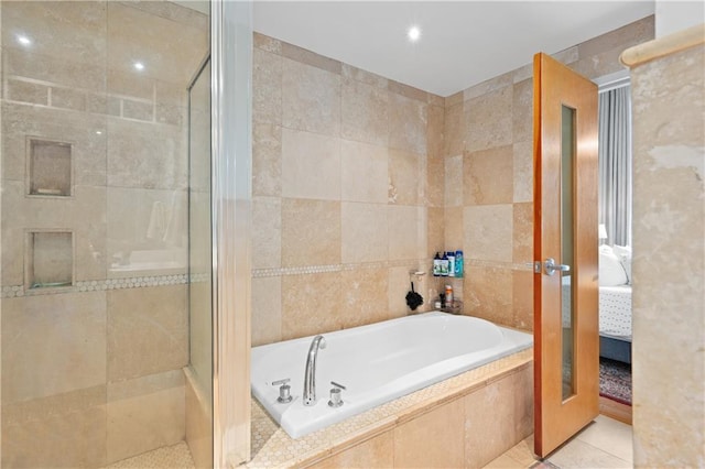 bathroom with independent shower and bath, tile patterned flooring, and tile walls