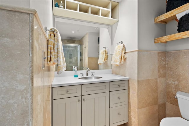 bathroom featuring vanity, toilet, a shower with shower door, and tile walls