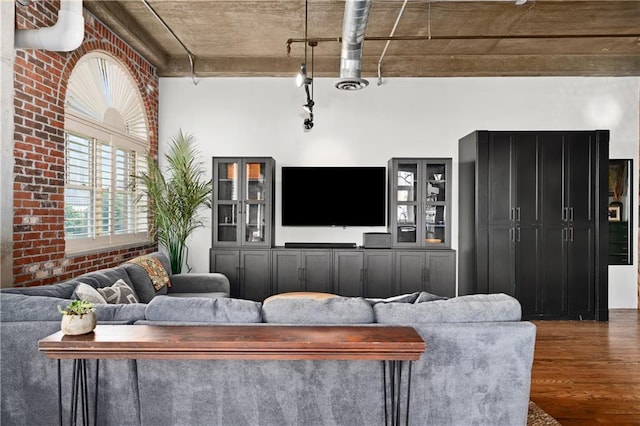 living room featuring brick wall and dark wood-type flooring