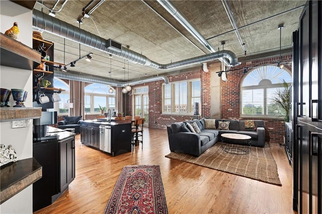 interior space featuring sink, light wood-type flooring, track lighting, and brick wall