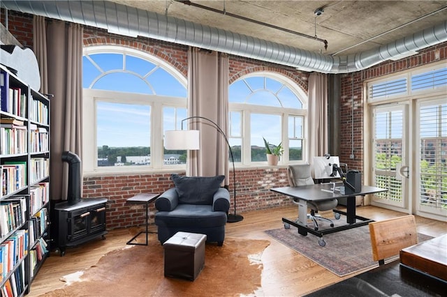 living area featuring a wood stove, light hardwood / wood-style floors, and brick wall