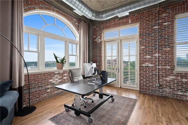 home office featuring light hardwood / wood-style flooring and brick wall