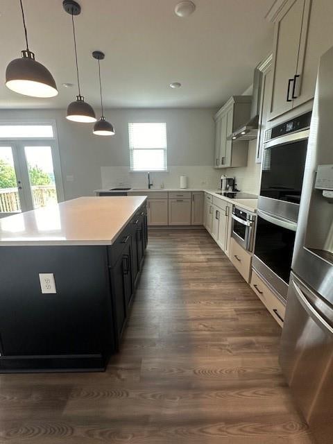 kitchen with pendant lighting, stainless steel refrigerator with ice dispenser, wood-type flooring, and a healthy amount of sunlight