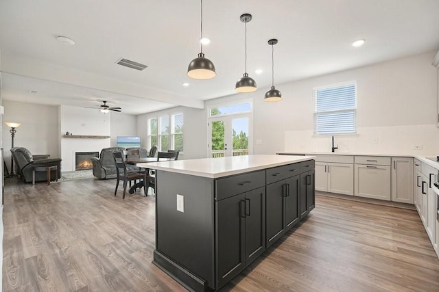 kitchen with pendant lighting, a kitchen island, ceiling fan, light hardwood / wood-style floors, and gray cabinetry