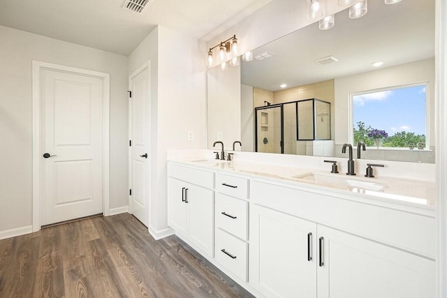 bathroom featuring a shower with shower door, wood-type flooring, and dual vanity