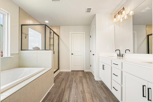 bathroom with wood-type flooring, vanity, and independent shower and bath