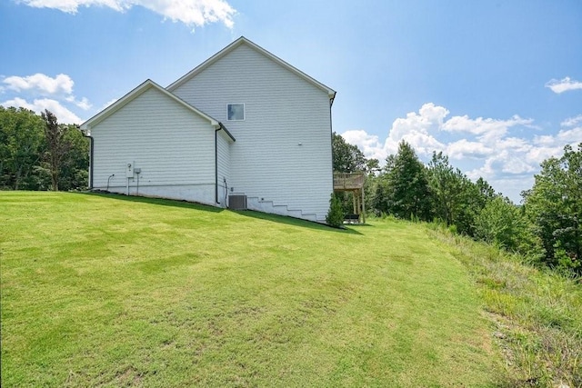 view of side of home featuring central AC unit and a yard