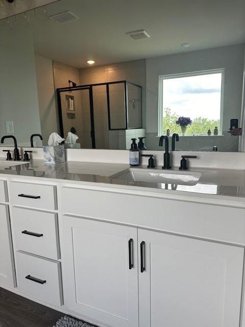 bathroom with hardwood / wood-style floors, a shower with shower door, and double vanity