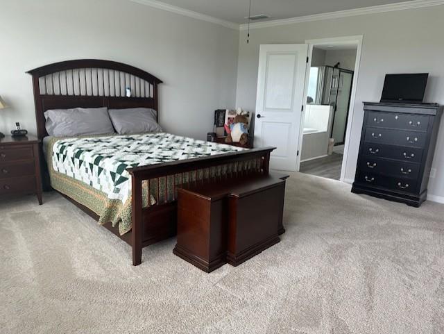 carpeted bedroom featuring ensuite bathroom and ornamental molding