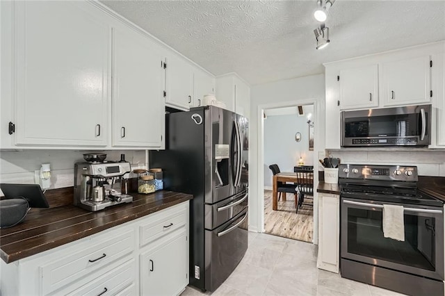 kitchen with white cabinets, stainless steel appliances, and a textured ceiling