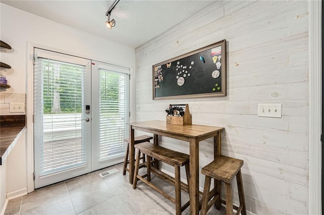 dining area featuring wood walls, visible vents, and french doors