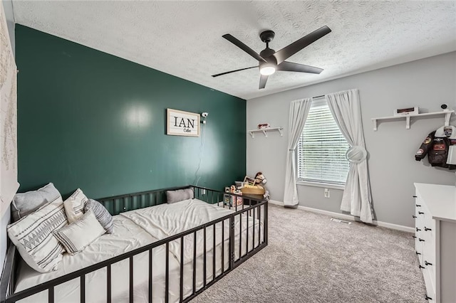 carpeted bedroom featuring visible vents, a ceiling fan, a textured ceiling, and baseboards
