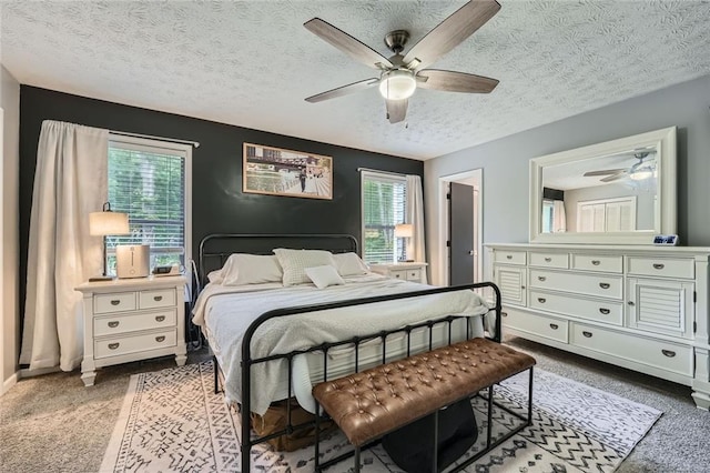 bedroom with ceiling fan, multiple windows, a textured ceiling, and light colored carpet
