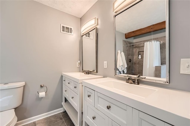 bathroom featuring a tile shower, a sink, toilet, a textured ceiling, and visible vents