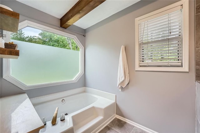 bathroom with baseboards, tile patterned flooring, beam ceiling, and a garden tub