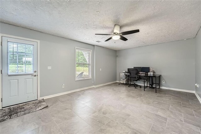 office area featuring baseboards, a ceiling fan, a textured ceiling, and a healthy amount of sunlight