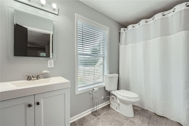 full bath with a healthy amount of sunlight, vanity, baseboards, and toilet