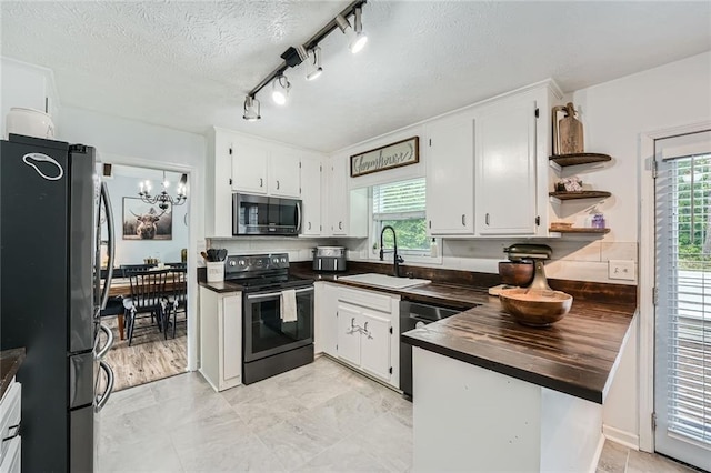 kitchen featuring a sink, stainless steel appliances, white cabinetry, and a wealth of natural light
