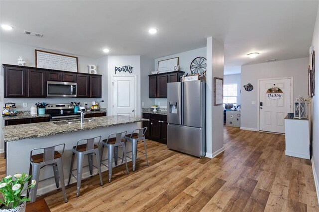 kitchen featuring appliances with stainless steel finishes, sink, a kitchen breakfast bar, a center island with sink, and dark brown cabinets