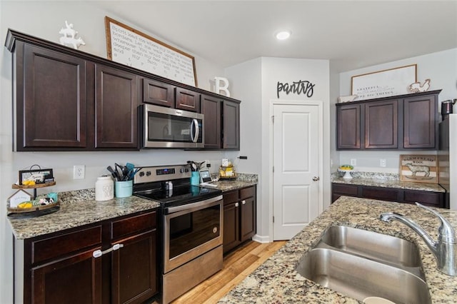 4770 Alford Commons, Cumming, GA 30028 - kitchen featuring stainless steel appliances, a sink, light wood-style floors, dark brown cabinets, and light stone countertops