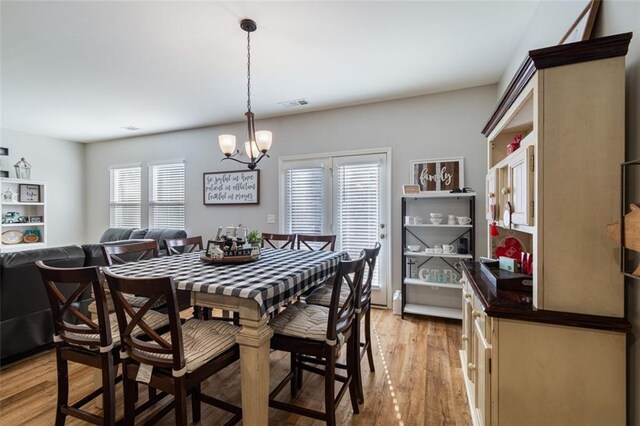 dining area featuring plenty of natural light, light hardwood / wood-style flooring, and an inviting chandelier