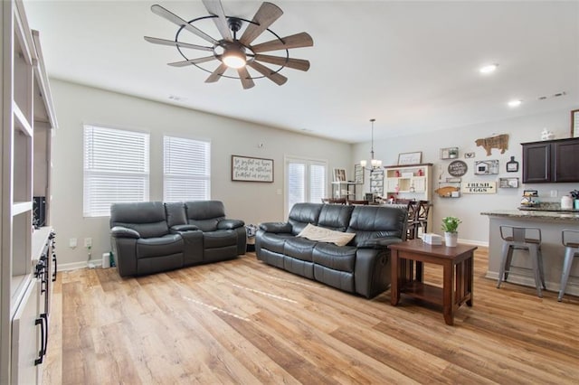 living room featuring light hardwood / wood-style floors and ceiling fan with notable chandelier