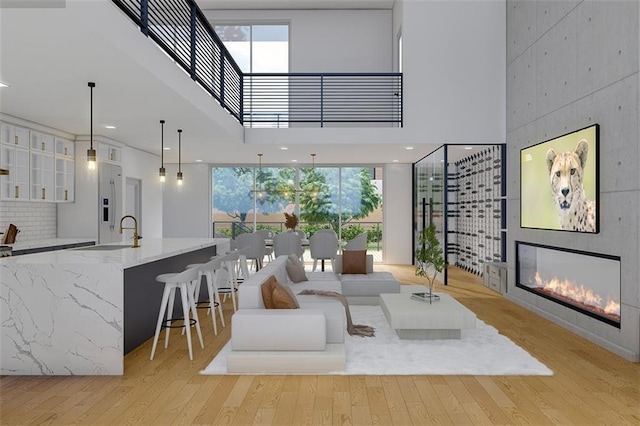 living room with a tiled fireplace, a healthy amount of sunlight, sink, and a high ceiling