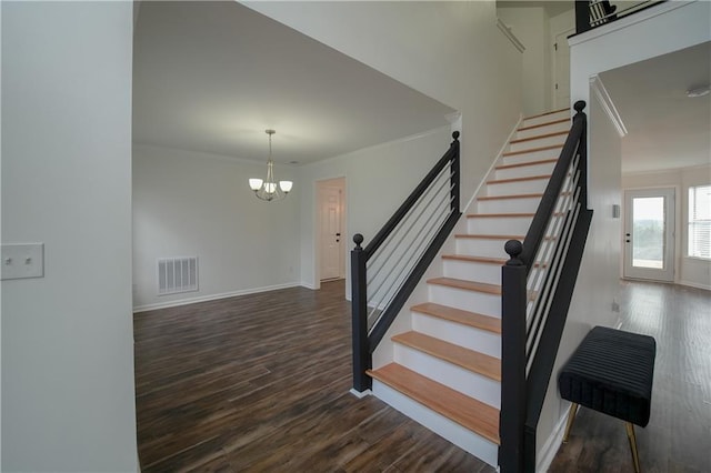 stairway with crown molding, wood-type flooring, and a chandelier